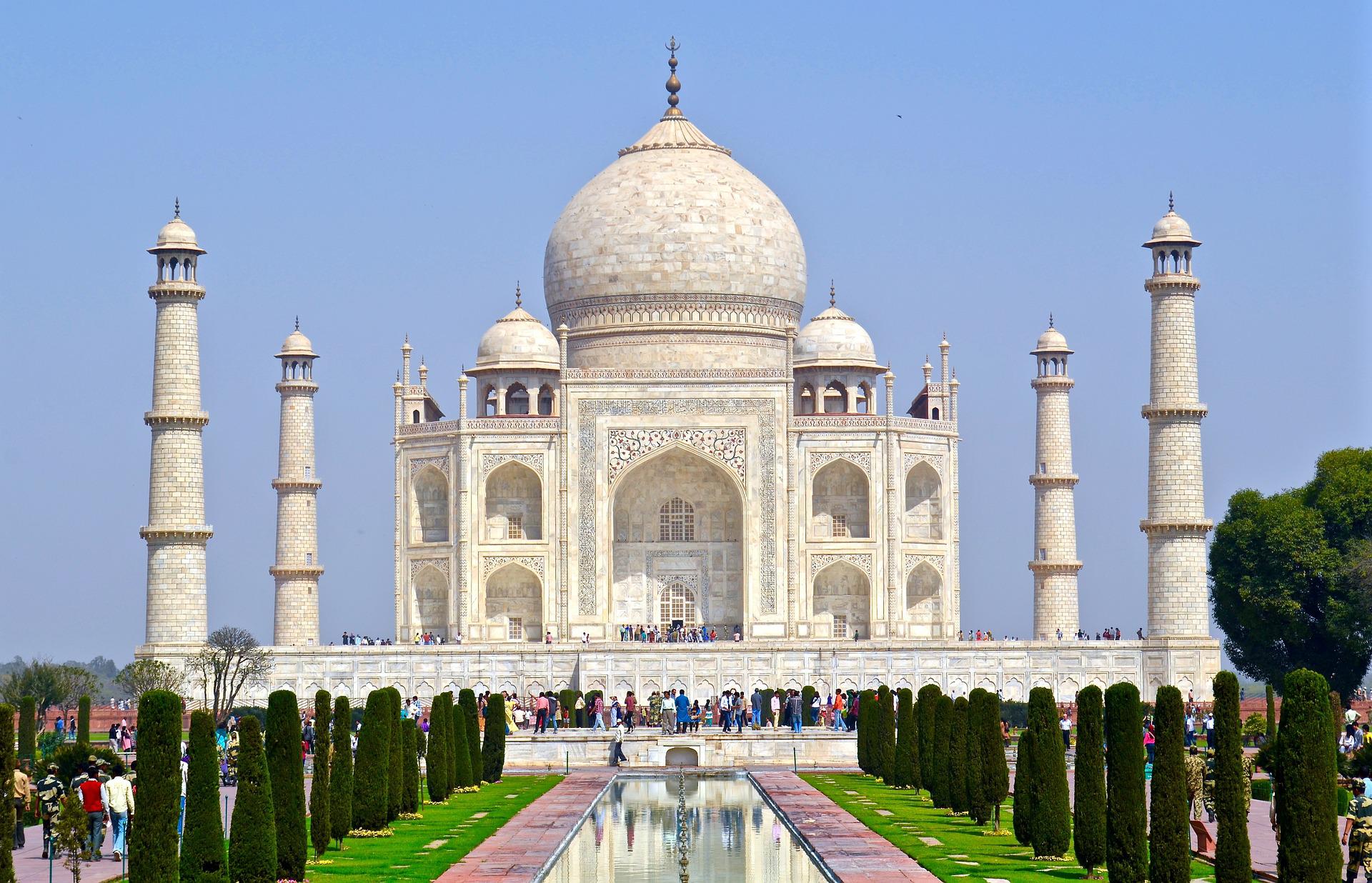 Pristine white marble Taj Mahal reflecting in gardens under clear blue sky